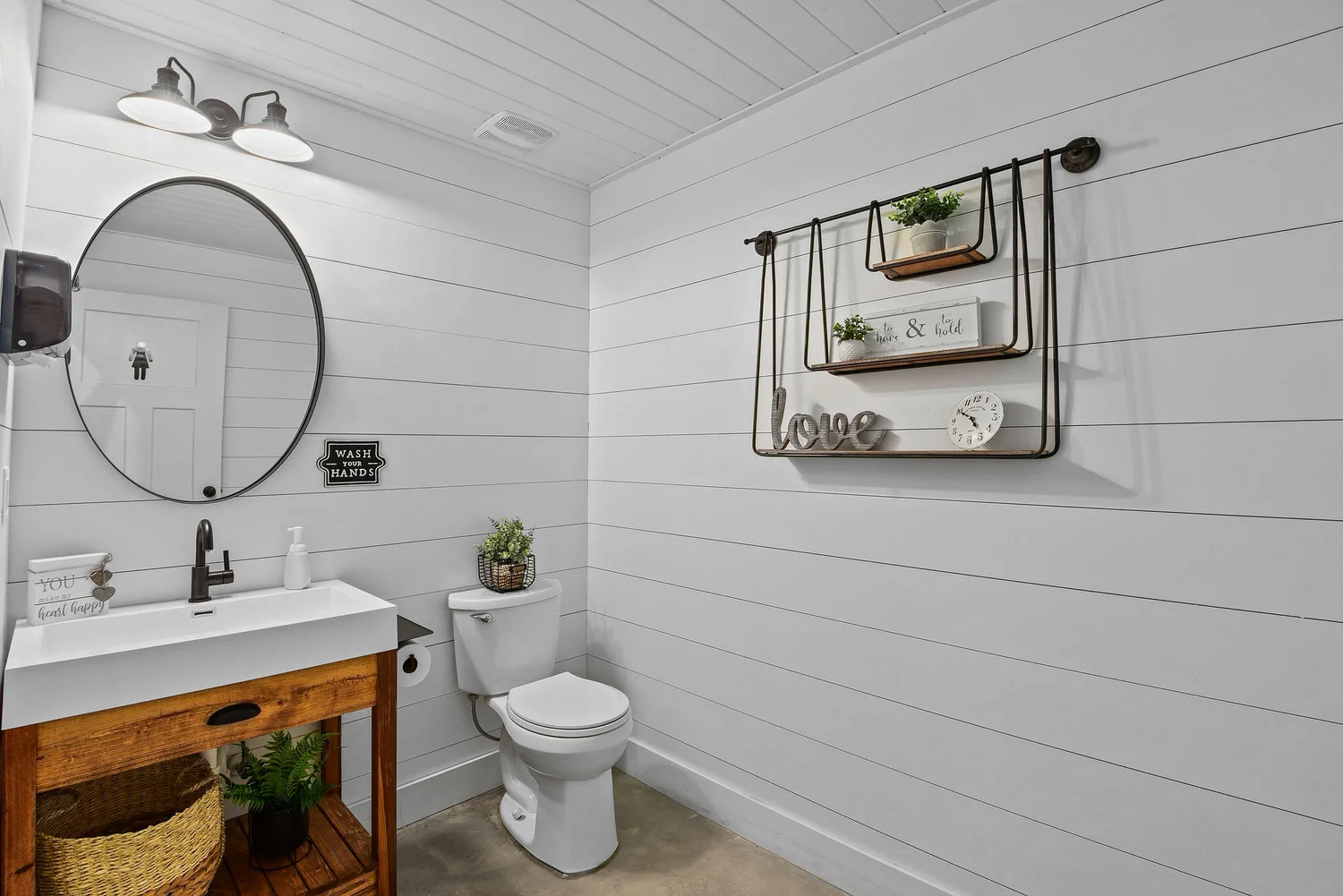 One of the two indoor restrooms, white shiplap with a round mirror
