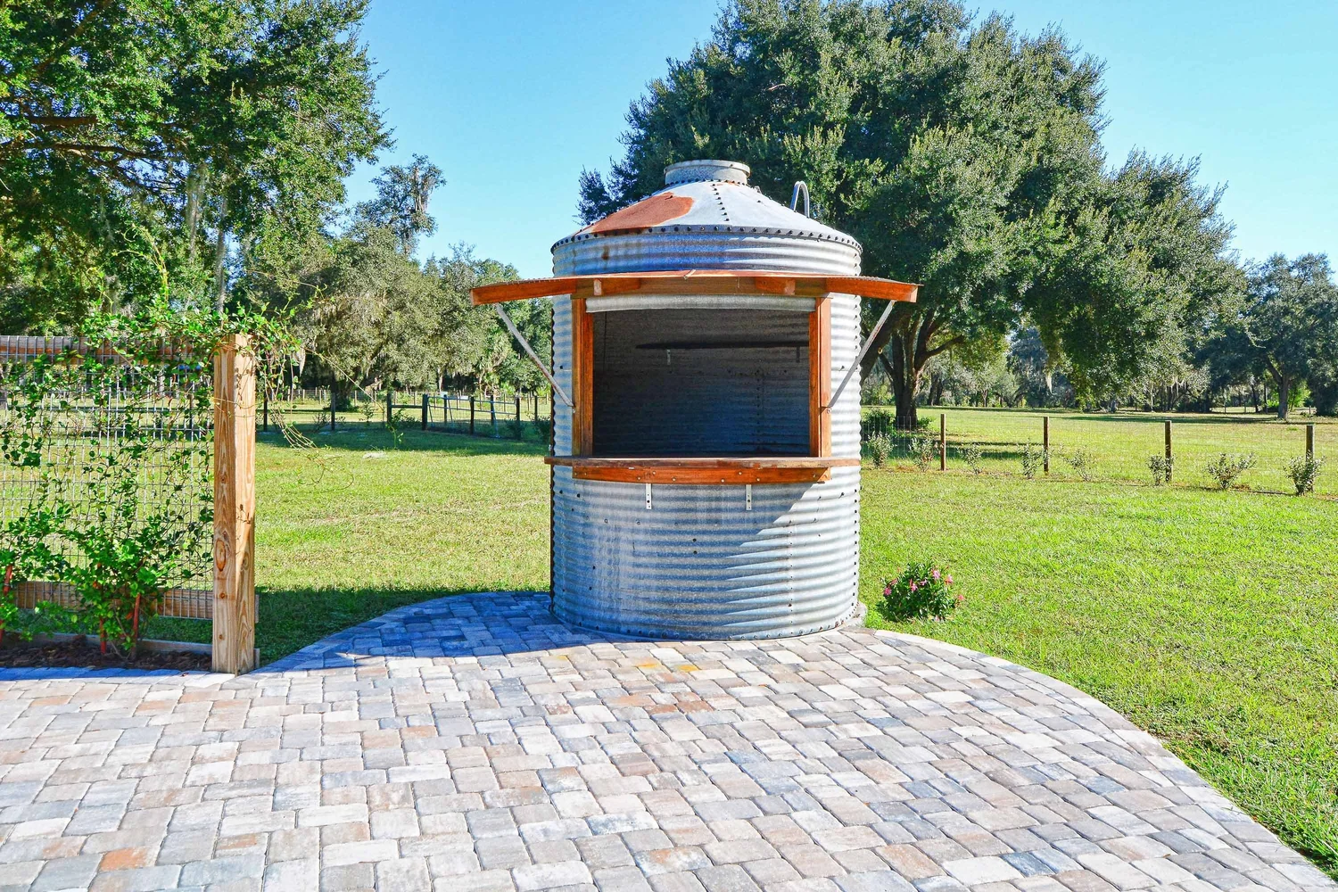 A round corrugated-metal silo bar beside the paver patio