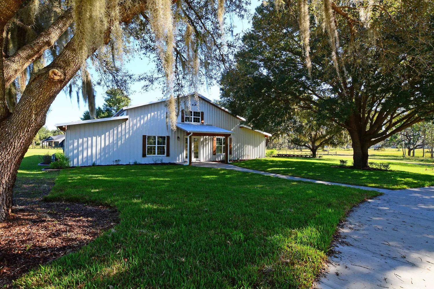 The barn framed by Spanish-moss oaks at the end of a curving drive